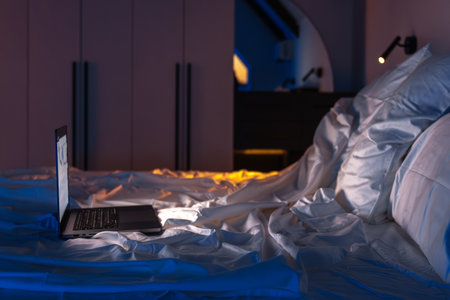 Laptop side profile on bed, blue loft interior. Late talk.の写真素材