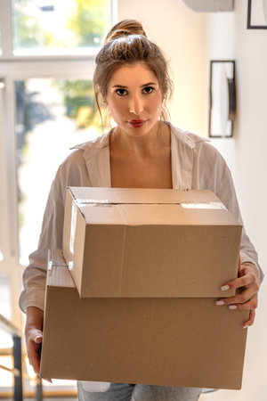 Portrait of young woman with boxes on stairs. Online unboxing.