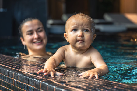 Baby at pool edge with tongue out. Playful moment.