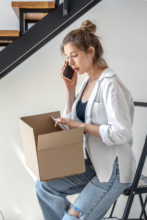 Woman with open box and smartphone. One person, focus.