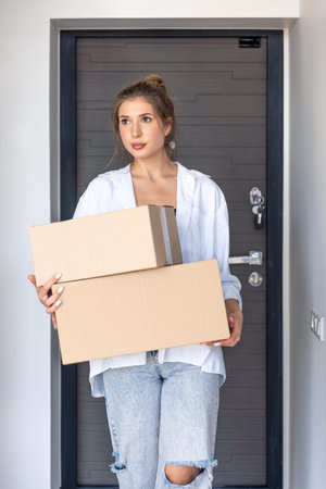 Young woman with two boxes by the apartment door. Home delivery.