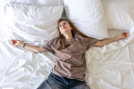 Teen on white bed in dreamy morning. Stretch and freedom.の写真素材