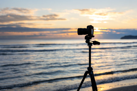 Camera on tripod by the sea at sunset. Tripod with camera.