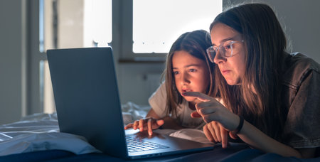 Two girls study a laptop, focused search. Concentrated girl pointing.の写真素材