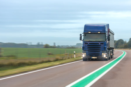 Blue truck on rural highway with green line. Logistics in motion.の写真素材