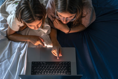 Two girls over the keyboard, top view. Girl taps the trackpad.の写真素材