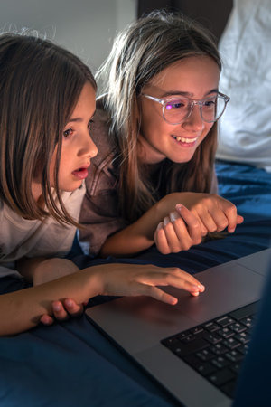 Girls by laptop celebrate a find. Happy girl on screen.