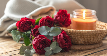 Romantic cozy scene with candle and red roses on wooden table. Love mood.の写真素材