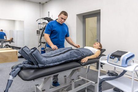 Doctor supports pressotherapy for woman in rehab clinic. Body recovery.