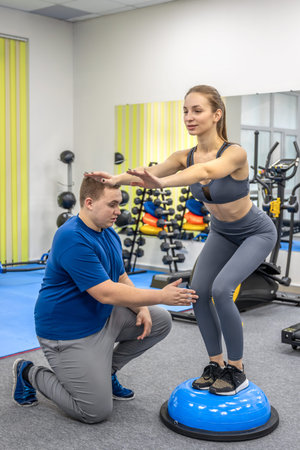 Doctor assists patient with balance exercise on platform. Stability therapy.