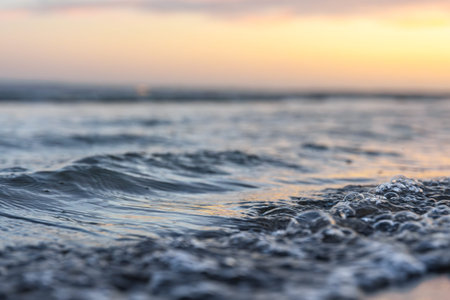 Macro shot of sea wave at sunset. Soft foam and bubbles on the shore.