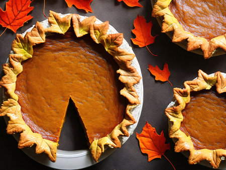 Freshly baked pumpkin pies for Thanksgiving with autumn leavesの写真素材