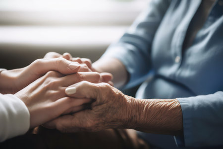 Close-up of senior woman holding hands with her adult daughter.の素材