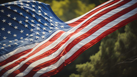 American flag waving in the wind on a background of green trees.
