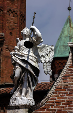 Medieval statue of an angel with a trumpet decorating the facade of the Cremona Cathedral.の写真素材