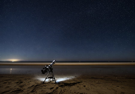 Astronomical telescope on a quiet beach at night under a clear, star-filled sky, perfect for stargazingの素材