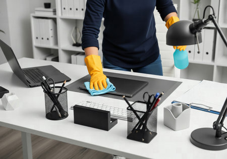 Person in Yellow Gloves Cleaning Office Desk Surface and Laptop with a Blue Microfiber Cloth and Sprayの素材