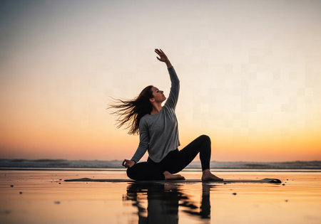 Dynamic profile shot of a woman in a low lunge yoga pose on a beach at sunset, with her hair flowing in the windの素材