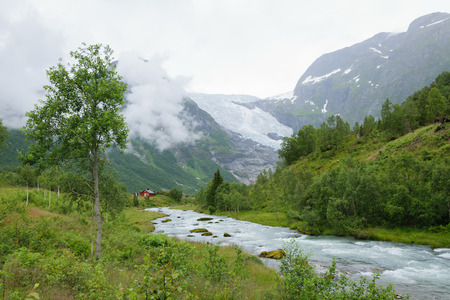 house near the river and snowy mountainsの写真素材