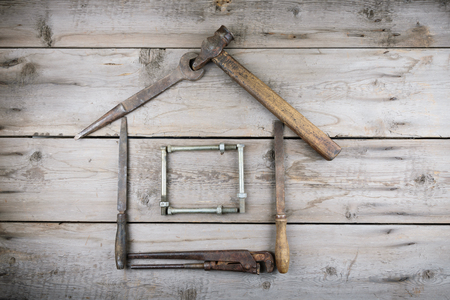 The concept of a house under construction. Old wooden desktop. Old rusty carpentry toolsの写真素材