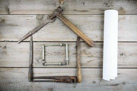 The concept of a house under construction. Old wooden desktop. Old rusty carpentry toolsの写真素材