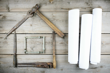 The concept of a house under construction. Old wooden desktop. Old rusty carpentry toolsの写真素材