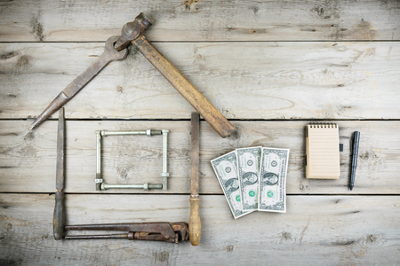 The concept of a house under construction. Old wooden desktop. Old rusty carpentry toolsの写真素材