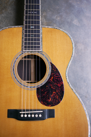 Acoustic guitar resting against a concrete wallの写真素材