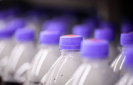 Soft drink bottles with purple caps on shelf in a supermarket. Selective focus.の写真素材