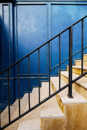 Black metal rail with the yellow stairs againt the blue classic wall.の写真素材