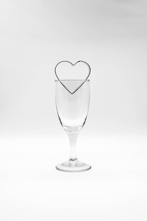 Metal heart frame over wine glass. Selective focus.の写真素材