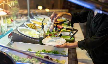 woman hands holding tweezer and dish rocket salad in the restaurant.の写真素材