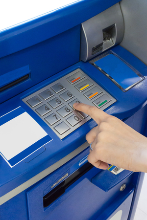 Hand of a woman using an ATM. Woman using an atm machine pressing her password.の写真素材