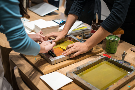 The art of paper workshop. Women hands scrapping colors on paper frame.