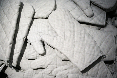 Many fabric kitchen gloves on sale. Selective focus.の写真素材