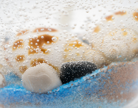 Decorative sea with colored sand, stones and seashells gel candle isolated on white background....