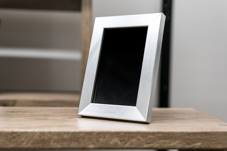 Black space on vertical silver aluminum frame on wooden deskの写真素材