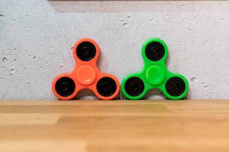 Orange and green fidget spinners againt the concrete background.の写真素材