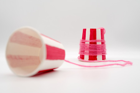 Red striped simple string phone made with white paper cups. Reuse materials for fun science experiment. Communication throwback concept.の写真素材