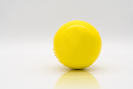Yellow stress ball rolling on reflection floor isolated on white background.の写真素材