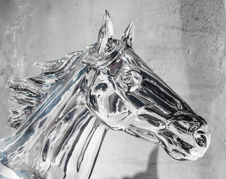 Head of silver horse statue. Shiny metal knight with reflection against painted wall for decoration. Sign of spirit and pride.の写真素材