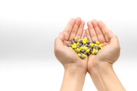 Woman hands holding group of yellow and gray capsule medicines in the palm