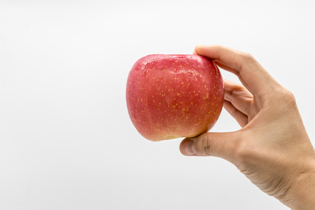 Woman hand holding fresh red apple isolated on white background with copy space.の写真素材