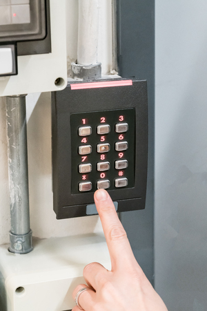 Pointing finger pressing the numeric keypad, Numpad, with red LED lights for staff get-in.