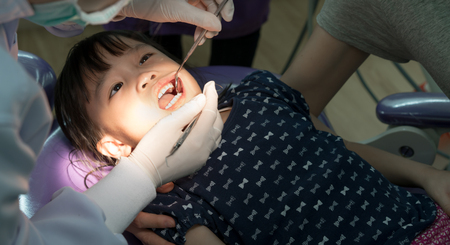 Teeth checkup at dentist's office. Dentist examining asian girls teeth in the dentists chairの写真素材