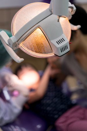 Close-up of the back of lamp in dental clinic while dentist examining asian girls teeth.の写真素材