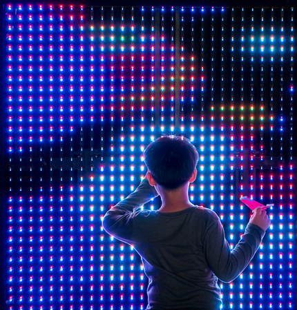 Asian boy playing with colorful led light interaction wallの写真素材