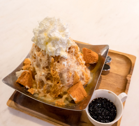 Thai tea shaved ice topped with whipped cream and white bread by tapioca pearl.  Popular Thai dessert for summer isolated on white background.の写真素材