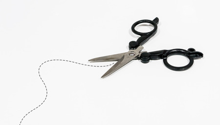 Black scissor is cutting by following the dash line isolated on white backgroundの写真素材