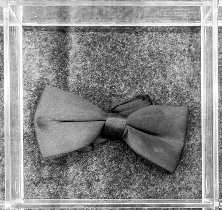 Black bow tie in an acrylic box against grey carpet backgroundの写真素材